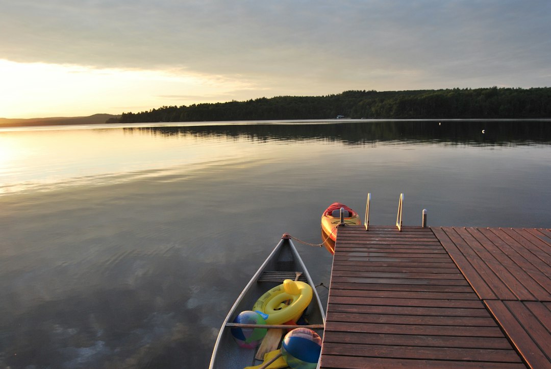 Small boat moored beside a wooden dock on a lake